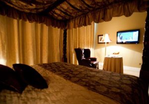 View of bedroom with tv on the wall and a small round dining table with a couch