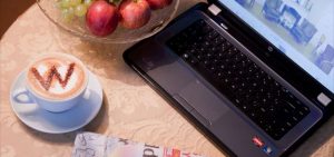 open laptop on the table with a cup of coffee next to it