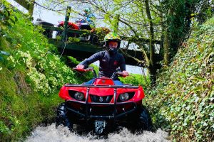 Boy on quad bike driving in low water