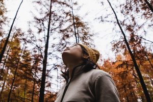 Female looking up at the sky standing in the forest