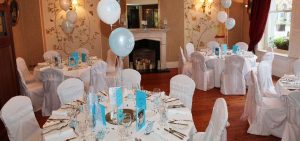 Round table with chairs and blue menus and balloons on the table