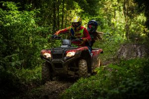 Couple on a quad bike going through the forest