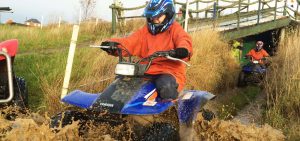 Boy on quad bike driving in low water