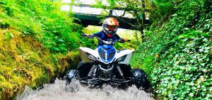 Boy on quad bike driving in low water